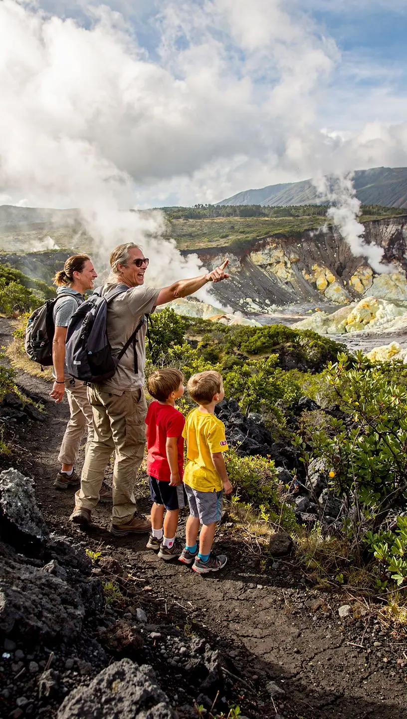 Солнце, заходящее за горизонт, освещающее вулканический пейзаж.